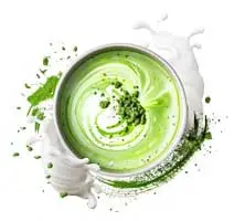 Schüssel mit grünem Matcha und Milchschaum, umgeben von spritzendem Matcha-Pulver und Milch.