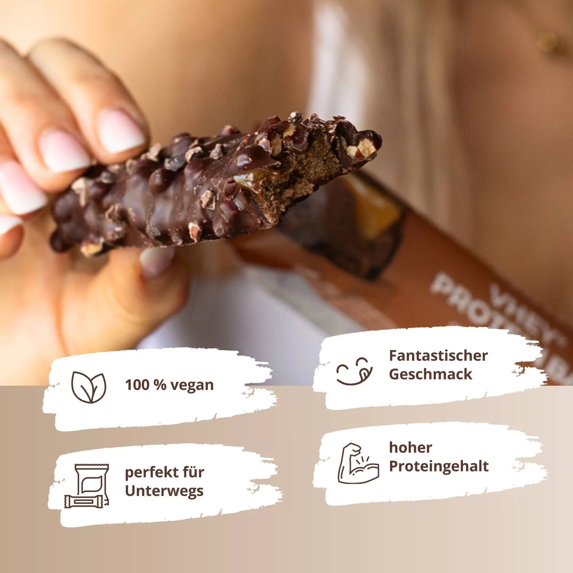 Eine Person hält die VHEY® Protein Bar Chocolate Caramel Crisp mit knackiger Oberfläche und nussiger Textur.